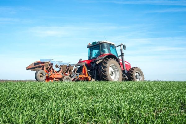 Tractor agricultural machine cultivating field.